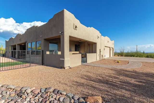 view of side of property with fence, a garage, stucco siding, and concrete driveway