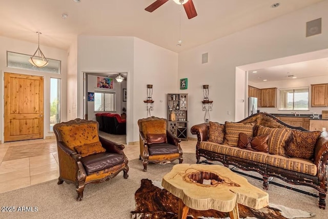 living room with light colored carpet, light tile patterned floors, a high ceiling, and ceiling fan