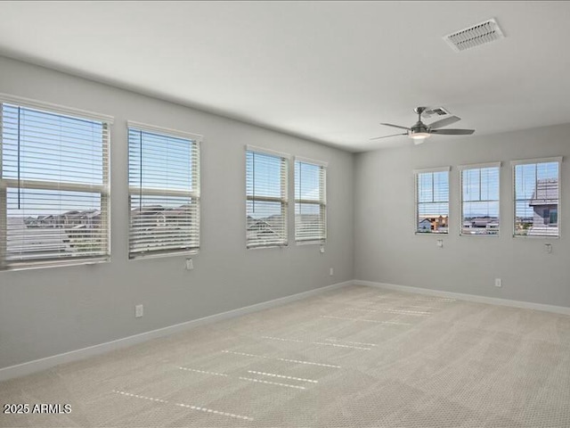 empty room with baseboards, visible vents, a wealth of natural light, and light colored carpet