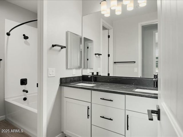 bathroom with double vanity, bathtub / shower combination, baseboards, and a sink