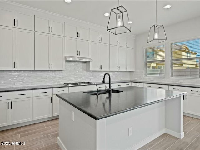 kitchen featuring under cabinet range hood, wood tiled floor, white cabinets, and a sink