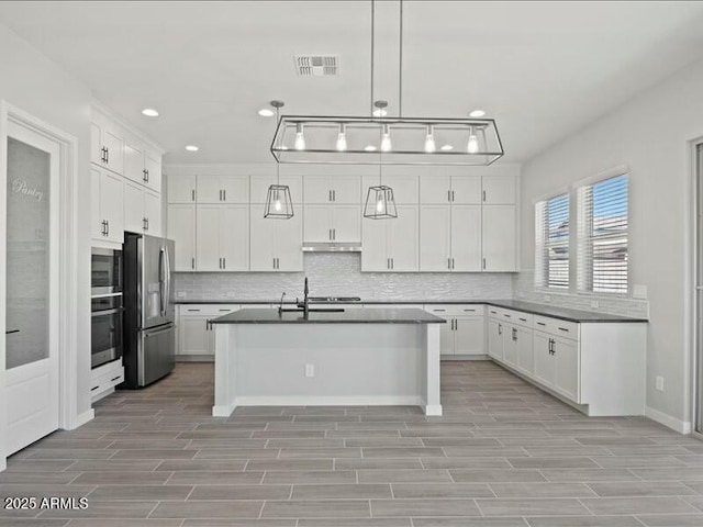 kitchen with visible vents, dark countertops, wood tiled floor, stainless steel appliances, and backsplash