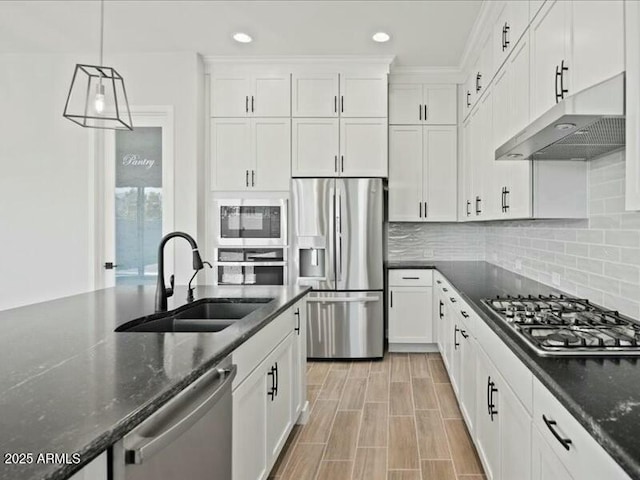 kitchen featuring tasteful backsplash, appliances with stainless steel finishes, under cabinet range hood, white cabinetry, and a sink