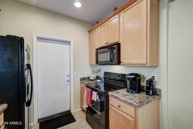 kitchen with black appliances, light tile patterned flooring, light stone countertops, and light brown cabinetry