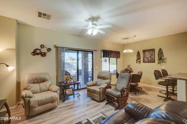 living room featuring ceiling fan with notable chandelier and light wood-type flooring