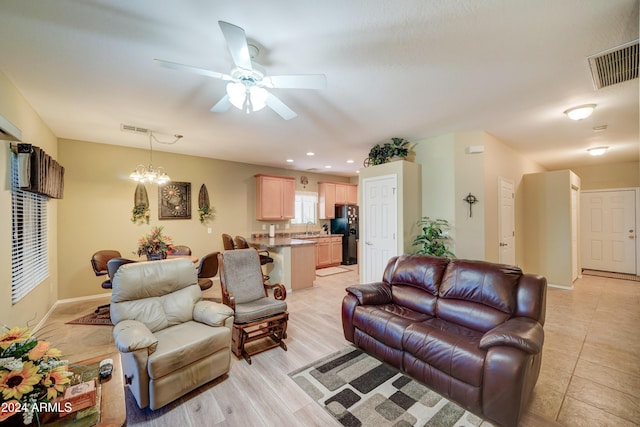 living room featuring ceiling fan with notable chandelier, sink, and light hardwood / wood-style flooring