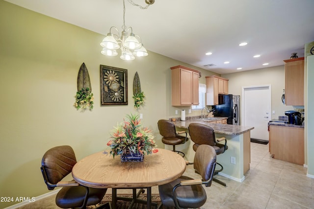 tiled dining space featuring sink and an inviting chandelier