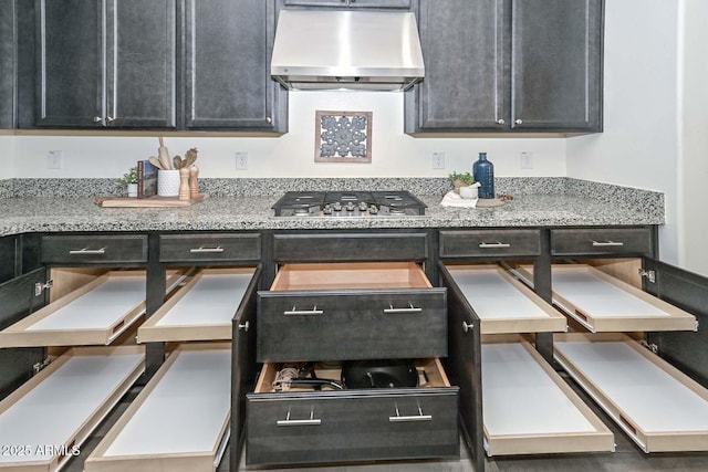 kitchen with stainless steel gas cooktop, light stone counters, and exhaust hood