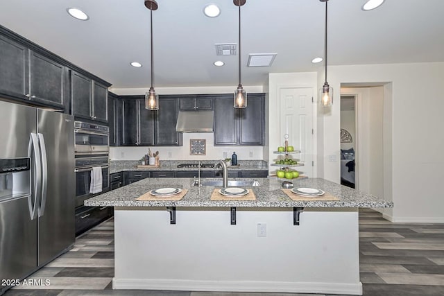 kitchen with under cabinet range hood, a breakfast bar, a sink, visible vents, and appliances with stainless steel finishes