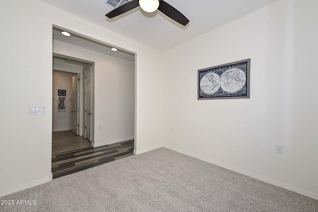 carpeted spare room with ceiling fan and baseboards