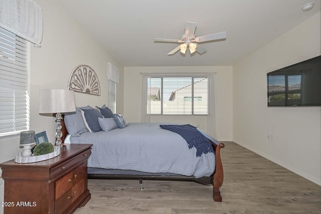 bedroom with light wood-style floors, ceiling fan, and baseboards