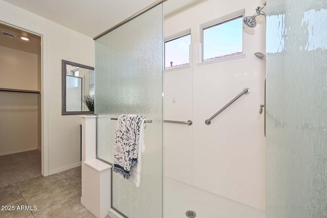 bathroom with tile patterned flooring, a walk in closet, and a shower stall