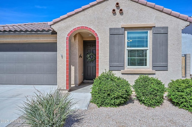 view of front of home featuring a garage, a tile roof, and stucco siding