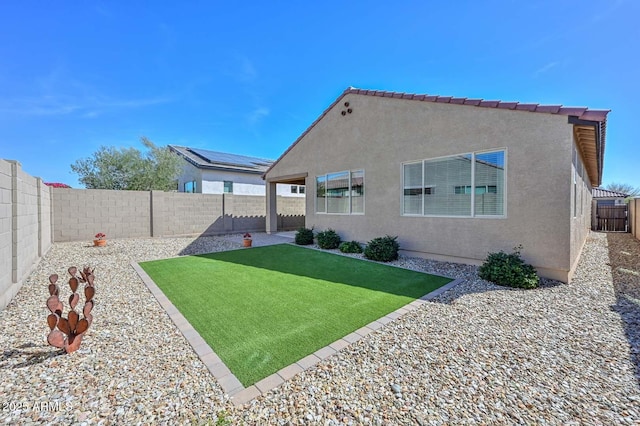 back of house featuring a fenced backyard, a lawn, and stucco siding