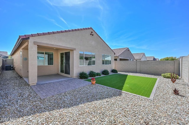 rear view of house featuring a yard, a fenced backyard, a patio, and stucco siding