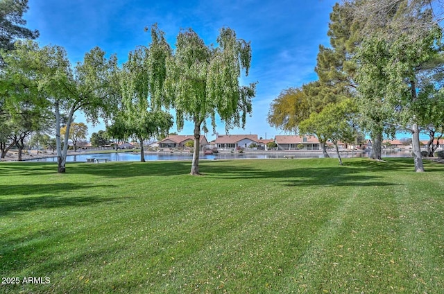 surrounding community with a water view and a lawn