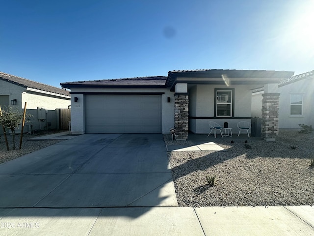 view of front of home featuring concrete driveway, stucco siding, stone siding, a garage, and fence