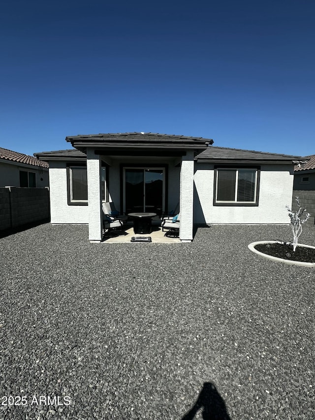 back of house featuring fence, a fire pit, a patio, and stucco siding