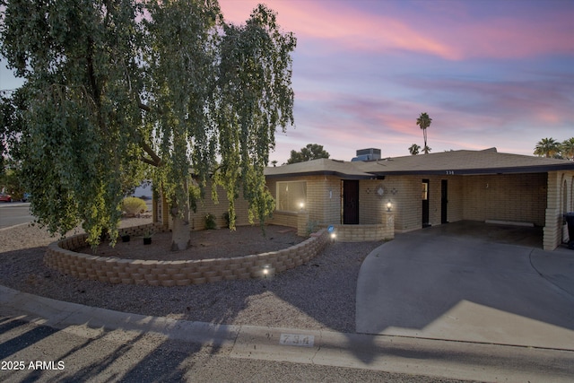 view of front of house featuring a carport, concrete driveway, and brick siding