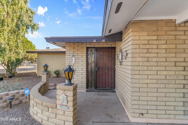 doorway to property with a patio and brick siding