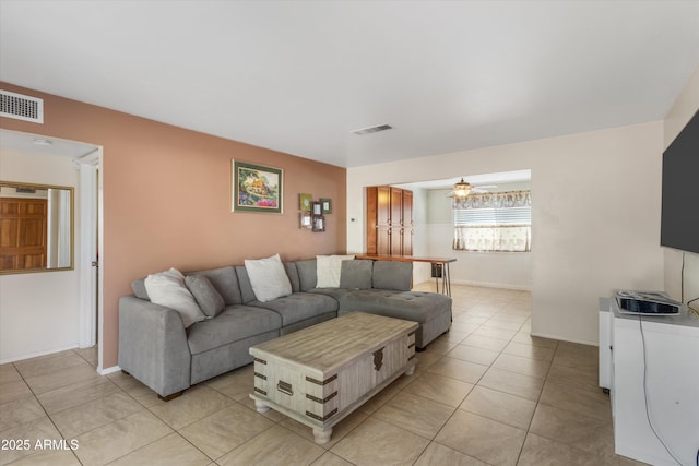 living room with light tile patterned flooring, visible vents, baseboards, and ceiling fan