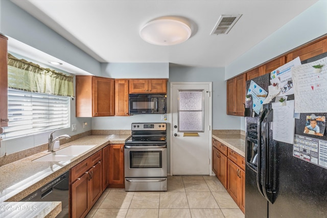 kitchen featuring visible vents, brown cabinets, black appliances, a sink, and light tile patterned floors