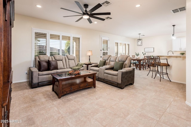 tiled living room featuring ceiling fan with notable chandelier