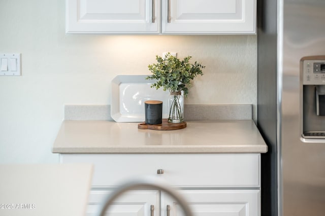 details featuring stainless steel refrigerator with ice dispenser and white cabinetry