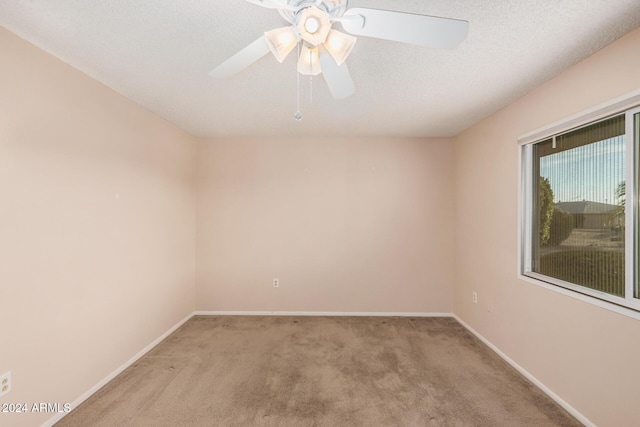 empty room featuring light carpet, ceiling fan, and a textured ceiling