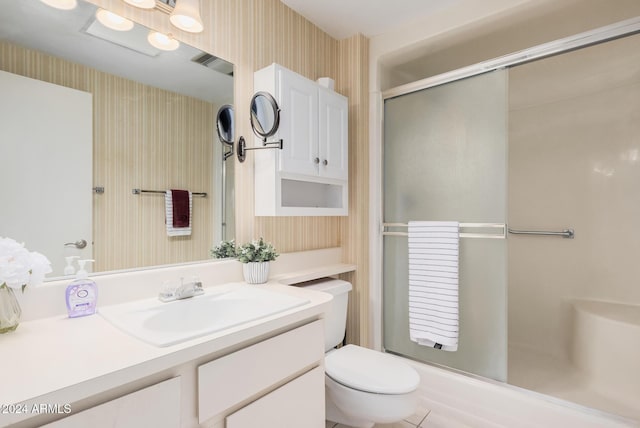 bathroom featuring vanity, toilet, and a shower with shower door