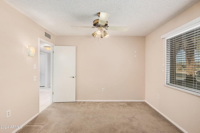 carpeted empty room with ceiling fan and a textured ceiling