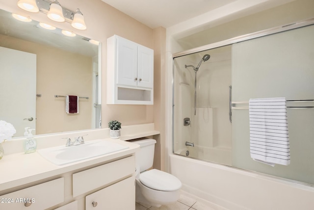 full bathroom with tile patterned flooring, vanity, bath / shower combo with glass door, and toilet