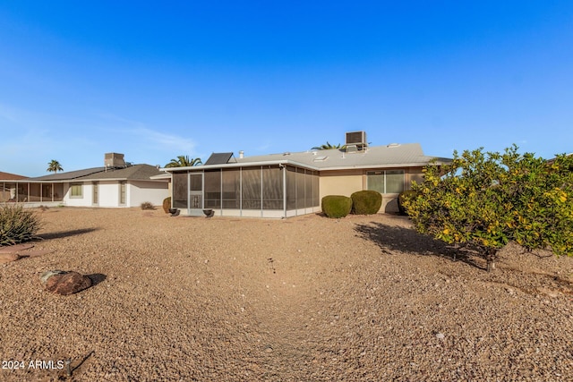 back of property with central AC and a sunroom