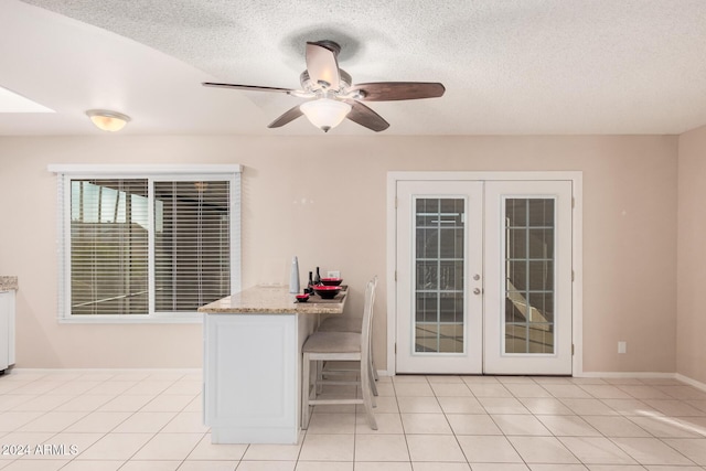 interior space featuring french doors, a textured ceiling, light tile patterned floors, and ceiling fan