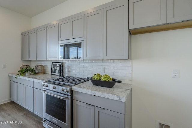 kitchen with tasteful backsplash, appliances with stainless steel finishes, gray cabinets, and light hardwood / wood-style flooring