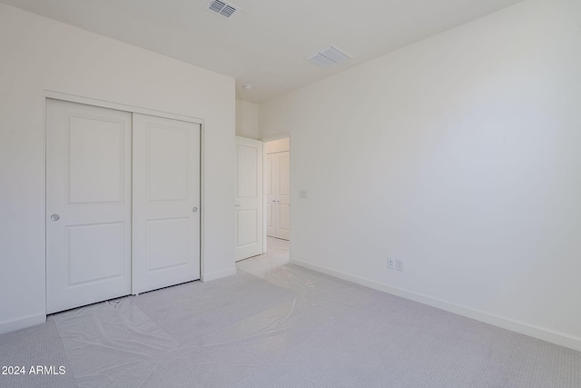 unfurnished bedroom with light colored carpet and a closet