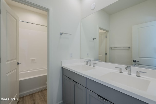 bathroom featuring vanity, hardwood / wood-style flooring, and washtub / shower combination