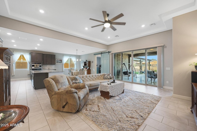 living room with light tile patterned flooring, a barn door, and ceiling fan