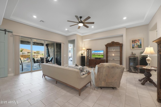 living room featuring ceiling fan and a barn door