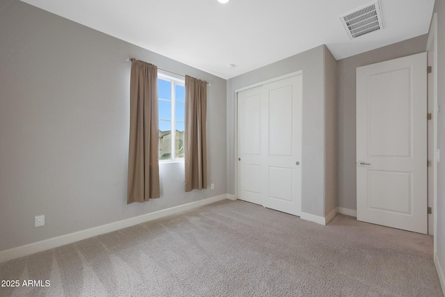 unfurnished bedroom featuring light colored carpet and a closet