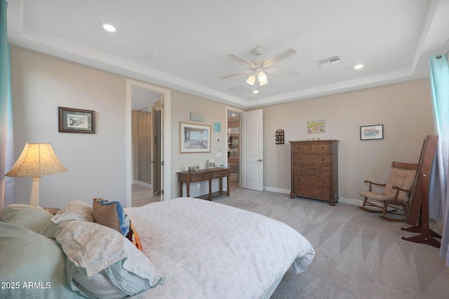 bedroom featuring a tray ceiling, light colored carpet, and ceiling fan