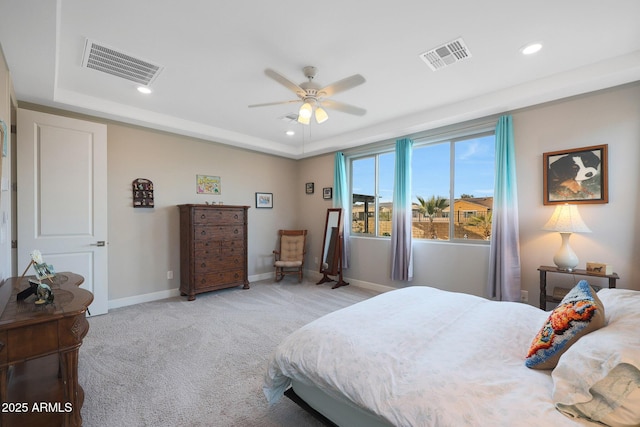 bedroom with ceiling fan, a tray ceiling, and light carpet