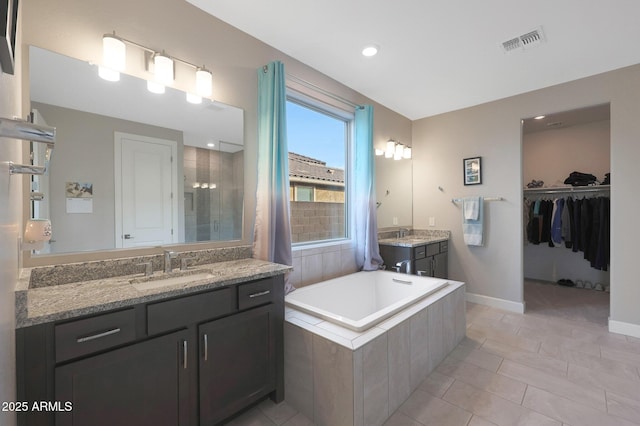 bathroom featuring vanity, a relaxing tiled tub, and tile patterned floors