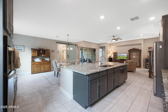 kitchen featuring pendant lighting, sink, a kitchen island with sink, light stone counters, and stainless steel appliances