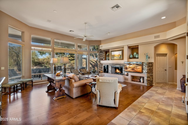 living room featuring a fireplace, ceiling fan, and light wood-type flooring