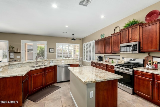 kitchen with appliances with stainless steel finishes, sink, a center island, light stone counters, and french doors