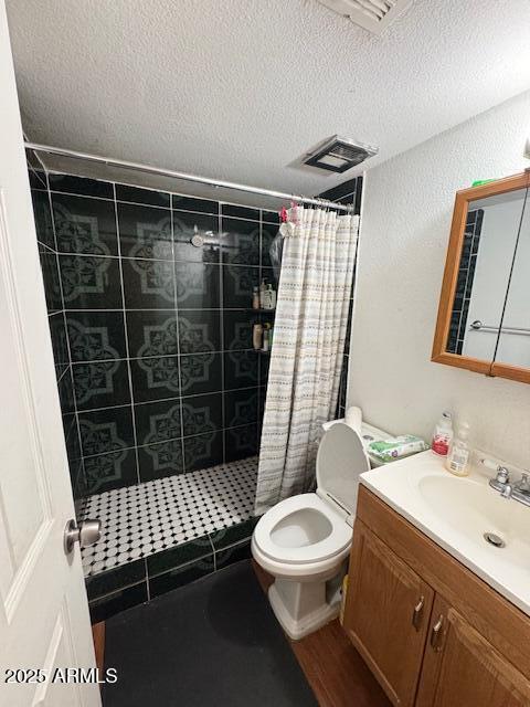 bathroom with vanity, toilet, curtained shower, and a textured ceiling