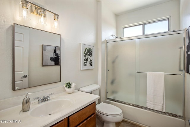 full bathroom featuring vanity, combined bath / shower with glass door, and toilet