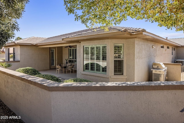 rear view of house with ceiling fan and a patio