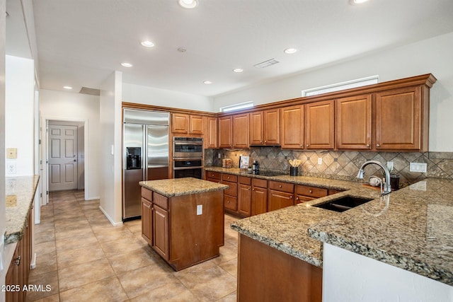 kitchen featuring a kitchen island, tasteful backsplash, sink, light stone counters, and stainless steel appliances